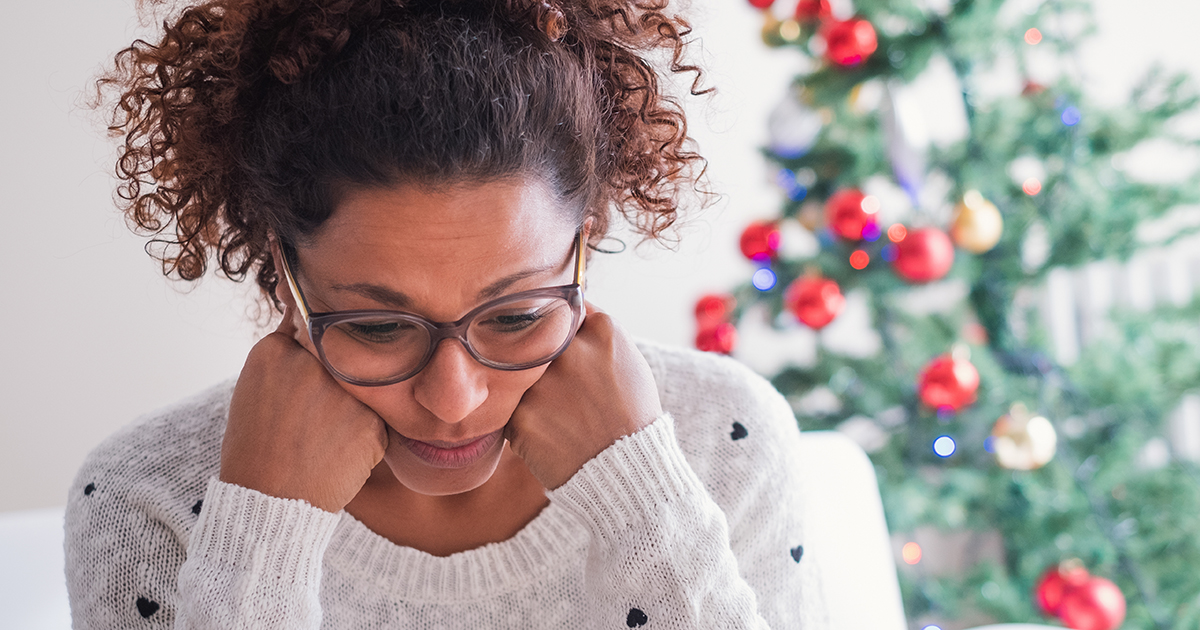 Worried black young woman sitting in the living room at home during christmas holiday