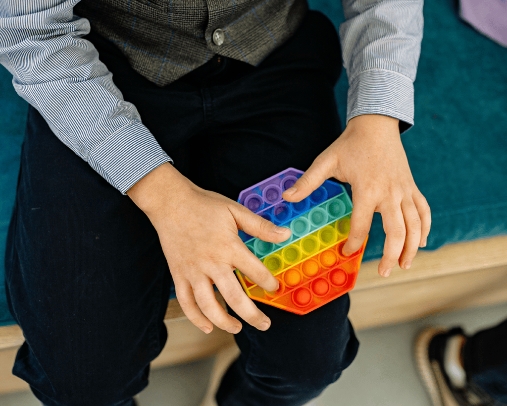 Hands pressing a colorful rainbow pop-it fidget toy for sensory relaxation.